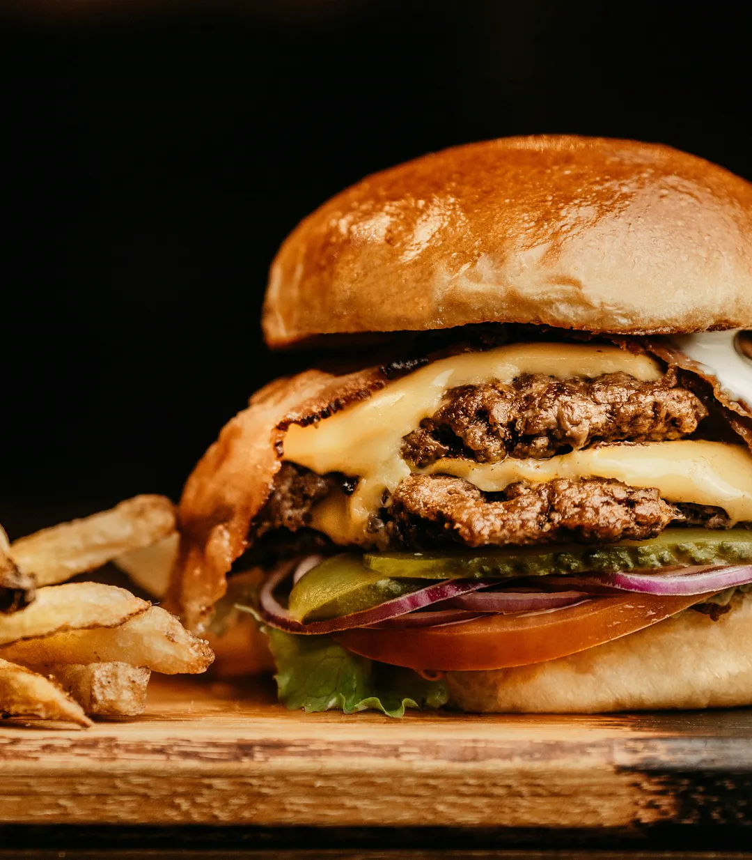 Double cheeseburger with fresh-cut fries on a wooden board