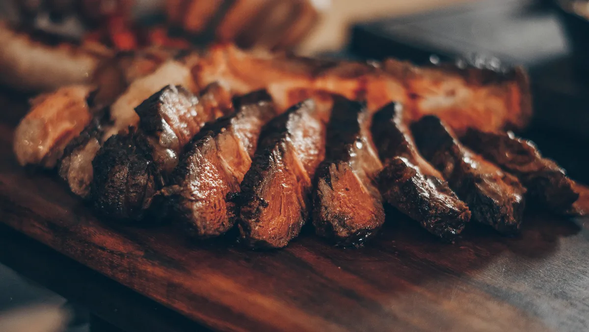 Grilled strip steak, sliced on a wooden board